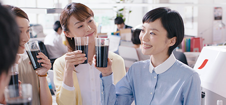 写真 職場 笑顔 みんながコーヒーを囲んでいる